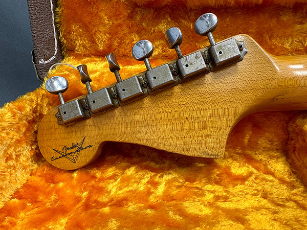 Close-up of vintage Fender Custom Shop guitar headstock with six tuning pegs on plush orange guitar case lining