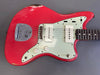 Vintage red electric guitar with white pickguard and dual single-coil pickups, showing worn finish and metal bridge plate, close-up view from Coffee House Guitars.