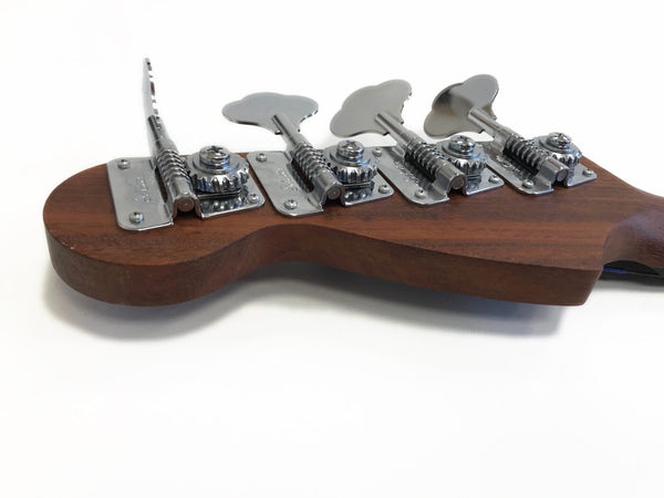 Close-up of chrome tuning pegs on the wooden headstock of a Coffee House Guitars bass guitar against white background