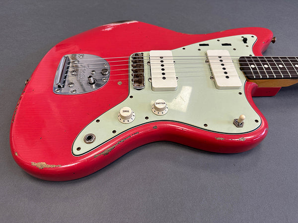 Vintage red electric guitar with white pickguard and dual single-coil pickups showing wear and scratches on body edges
