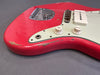 Close-up of red electric guitar body with white pickguard, tone and volume knobs, showing worn and chipped paint details on the edges.