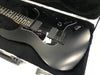 Black electric guitar with dual EMG pickups and volume knob, resting in a black padded hard case