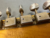 Close-up of vintage Kluson guitar tuning pegs on wooden headstock showing worn metal tuning keys and screws