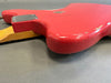Close-up of red electric guitar body with worn finish and maple neck on gray background showing back plate and aging details