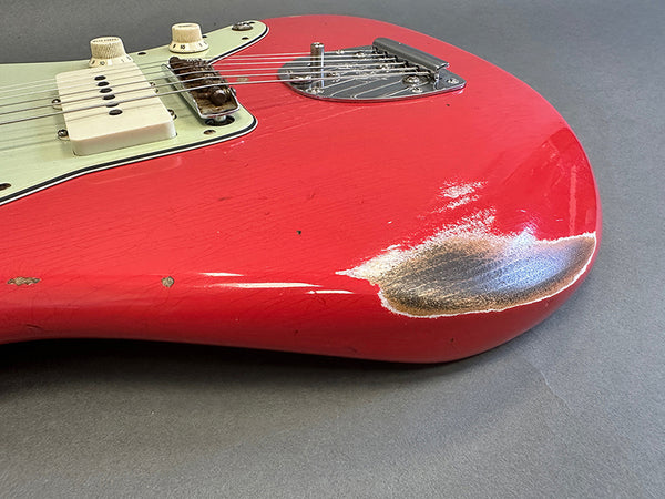 Close-up of red electric guitar body showing worn finish and scratches near bridge and control knobs