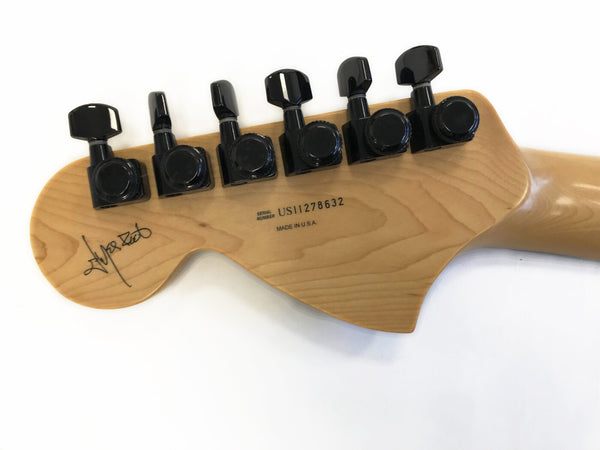 Back of natural wood guitar headstock with black tuning pegs, serial number US11278632, made in USA, and a signature on the left side.