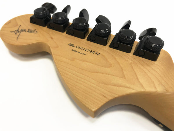 Close-up of guitar headstock with black tuning pegs, serial number US11278632, made in USA inscription, and signature on maple wood finish