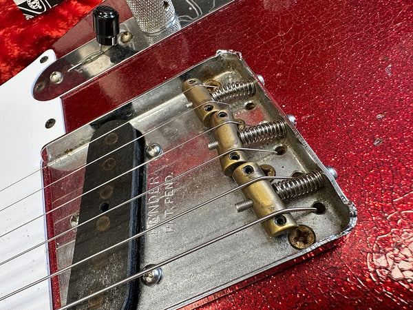 Close-up of vintage Fender Telecaster bridge and pickup on red sparkle guitar body with six strings and black control knob