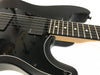 Close-up of black electric guitar body and fretboard with EMG pickups and white dot inlays on dark wood fingerboard