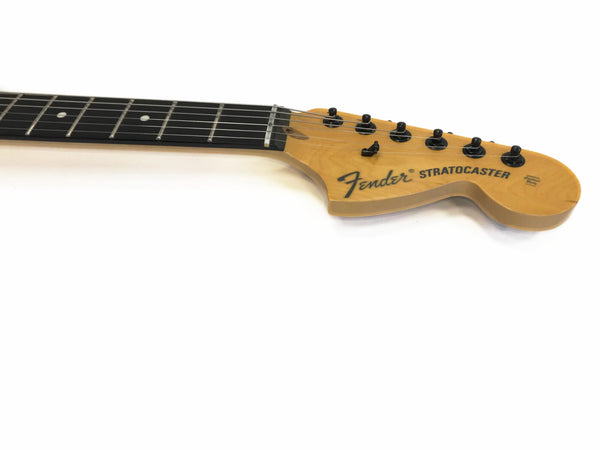 Close-up of Fender Stratocaster electric guitar headstock with tuning pegs and part of the fretboard on white background