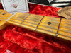 Close-up of vintage Fender guitar maple neck and frets on red plush case lining with certificate and desiccant packet in background