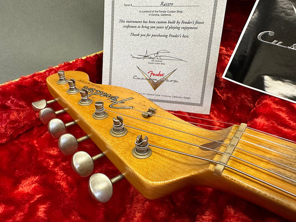 Fender Custom Shop guitar headstock with tuning pegs and certificate of authenticity on red plush case lining