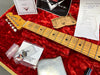 Close-up of Fender guitar neck with gold tuning pegs, placed on red velvet case interior with Fender certification, pre-sales checklist, and accessories for Fender Custom Shop guitar maintenance.