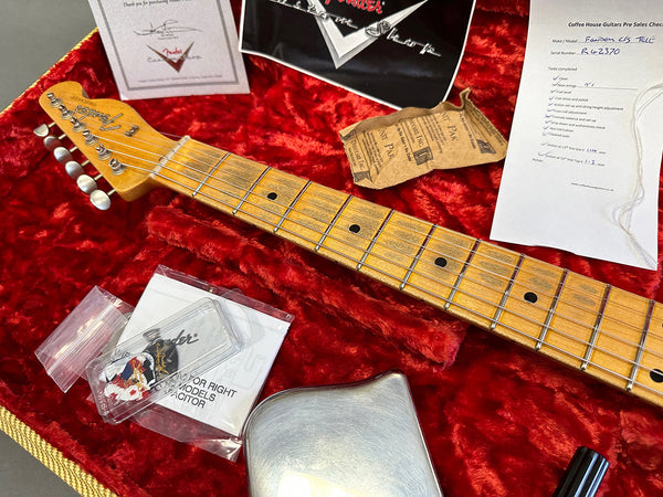 Close-up of Fender guitar neck with gold tuning pegs, placed on red velvet case interior with Fender certification, pre-sales checklist, and accessories for Fender Custom Shop guitar maintenance.
