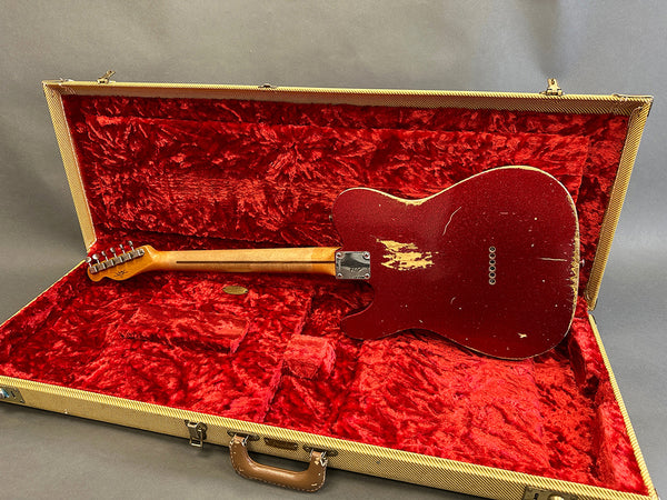 Vintage red electric guitar with worn finish inside open tan tweed guitar case lined with red plush interior