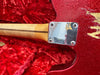 Close-up of maple neck joint plate with serial number on red sparkle finished electric guitar body in red plush case interior
