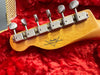 Close-up of vintage Fender Custom Shop guitar headstock with six tuning pegs on red plush case lining