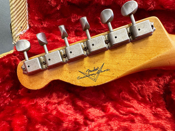 Close-up of vintage Fender Custom Shop guitar headstock with six tuning pegs on red plush case lining