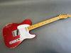 Vintage Fender Telecaster electric guitar with worn red sparkle finish and maple neck on gray background