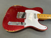 Red sparkle finish electric guitar with white pickguard and maple neck showing vintage wear and chipping on body edges, close-up of bridge and control knobs against gray background.