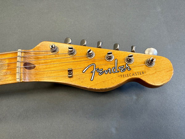 Close-up of Fender Telecaster guitar headstock with six tuning pegs on gray background