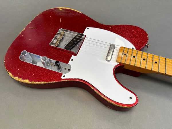 Red sparkle finish vintage electric guitar body with white pickguard and maple neck showing wear and aging, close-up on gray background