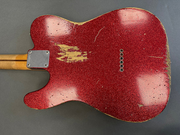Vintage red sparkle finish electric guitar body with visible wear and aging, string ferrules, and maple neck heel plate on gray background