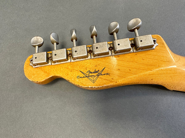 Close-up of vintage Fender Custom Shop guitar headstock with six metal tuning pegs on natural wood finish against gray background