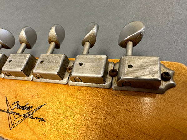 Close-up of vintage Fender Custom Shop electric guitar tuning pegs on wooden headstock with visible wear and original screws