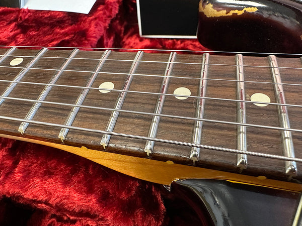 Close-up of vintage electric guitar rosewood fretboard with dot inlays and metal frets on red velvet background