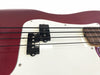 Close-up of red electric bass guitar body showing white pickguard, black pickups, and four black strings