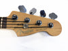 Close-up of Fender Precision Bass headstock with tuning pegs and strings on natural wood finish, made in USA.