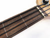 Close-up of acoustic bass guitar fretboard with black strings and wooden neck at Coffee House Guitars