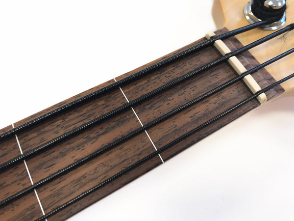 Close-up of acoustic bass guitar fretboard with black strings and wooden neck at Coffee House Guitars