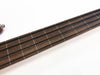 Close-up of rosewood guitar fretboard with four black strings and white fret markers on white background