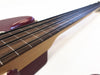 Close-up view of fretless bass guitar neck and strings with rosewood fingerboard and maroon body on white background