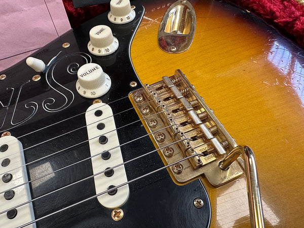 Close-up of vintage sunburst electric guitar bridge, volume and tone control knobs, and black pickguard with white single-coil pickups at Coffee House Guitars.
