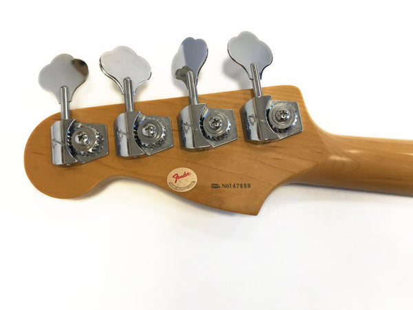 Back of Fender bass guitar headstock with chrome tuning pegs and serial number N6147659 on light wood finish