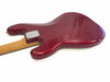 Back side of cherry red electric guitar body with wooden neck and metal neck plate against white background