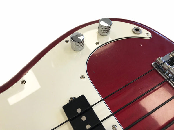 Close-up of red and white electric bass guitar body with chrome control knobs and black pickups, showcasing strings, input jack, and bridge details for Coffee House Guitars product listing.