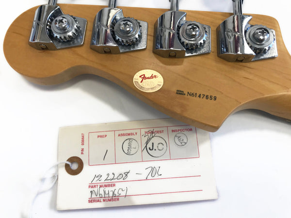 Close-up of Fender guitar headstock with chrome tuning pegs and serial number N6147659, includes Fender 50th anniversary gold sticker and assembly inspection tag with handwritten part number and serial number details.