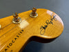 Close-up of Fender Stratocaster guitar headstock with gold tuning pegs and Stevie Ray Vaughan signature on natural wood finish