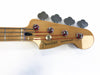 Fender Precision Bass guitar headstock with four tuning pegs and red-wrapped strings on natural wood finish against white background