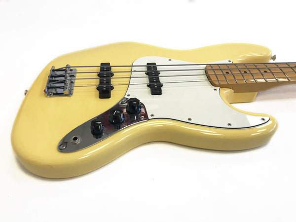 Cream-colored electric bass guitar with white pickguard, chrome control plate, and maple neck on white background