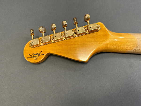 Fender Custom Shop guitar headstock with gold tuning pegs on natural wood finish neck against gray background