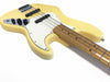 Close-up of yellow electric bass guitar body with maple neck, white pickguard, black pickups, and control knobs on white background