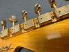 Close-up of vintage Fender guitar headstock tuning pegs in gold with Fender Custom Shop logo on wood grain neck