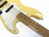 Close-up of yellow electric bass guitar body and maple fretboard with metal frets and black dot inlays on white background