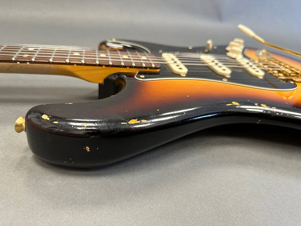Close-up of sunburst electric guitar body with worn and chipped paint finish, showing vintage relic details and gold hardware