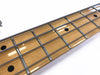 Close-up of electric bass guitar maple fretboard with metal frets and round black position markers on white background